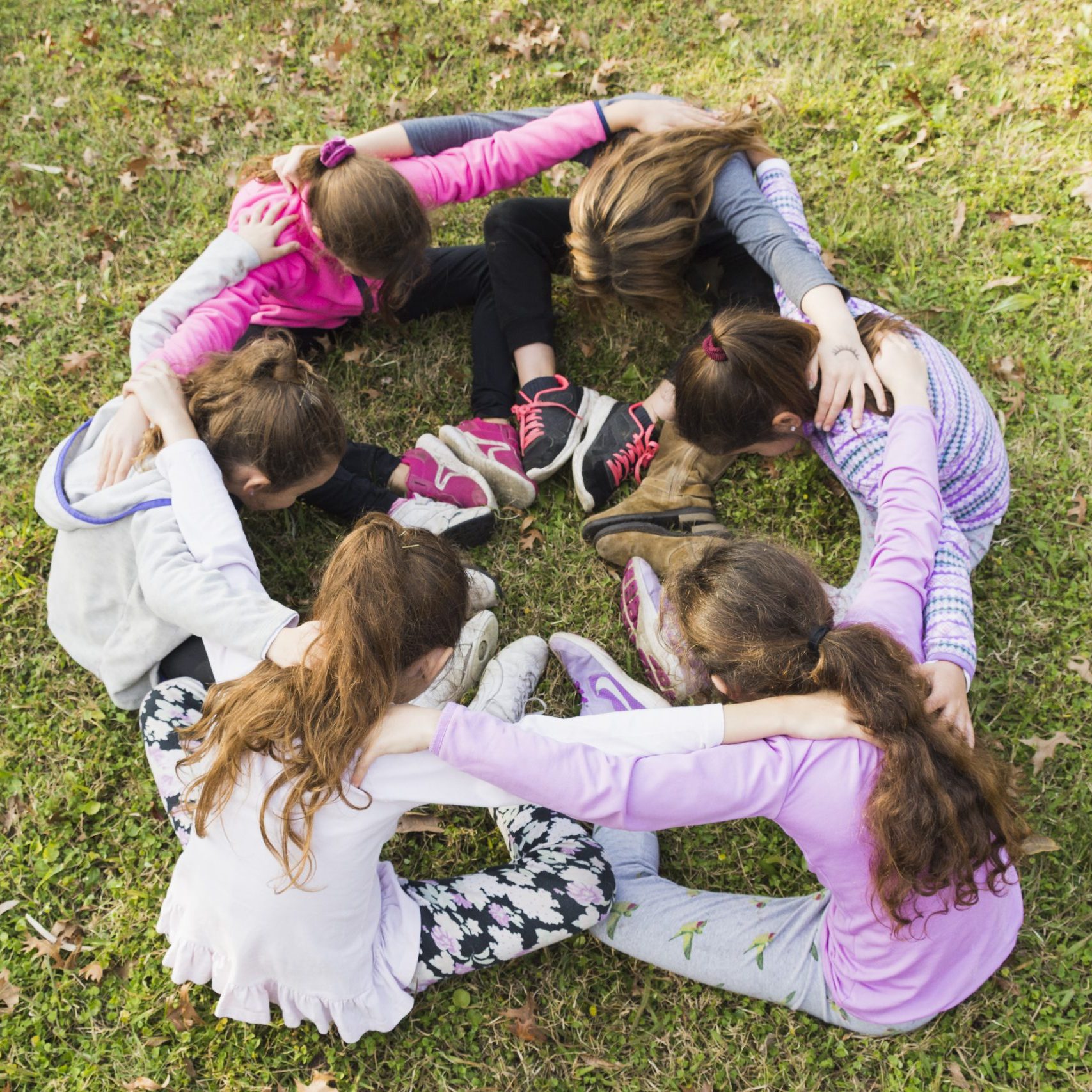 group-girls-sitting-together-huddle-green-grass